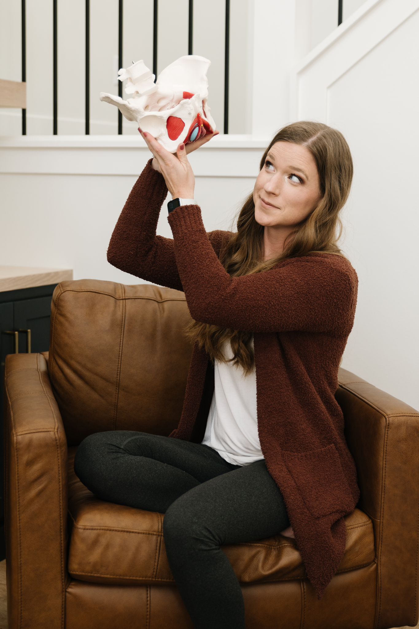 Image of therapist looking up at pelvic model with a curious look on her face.